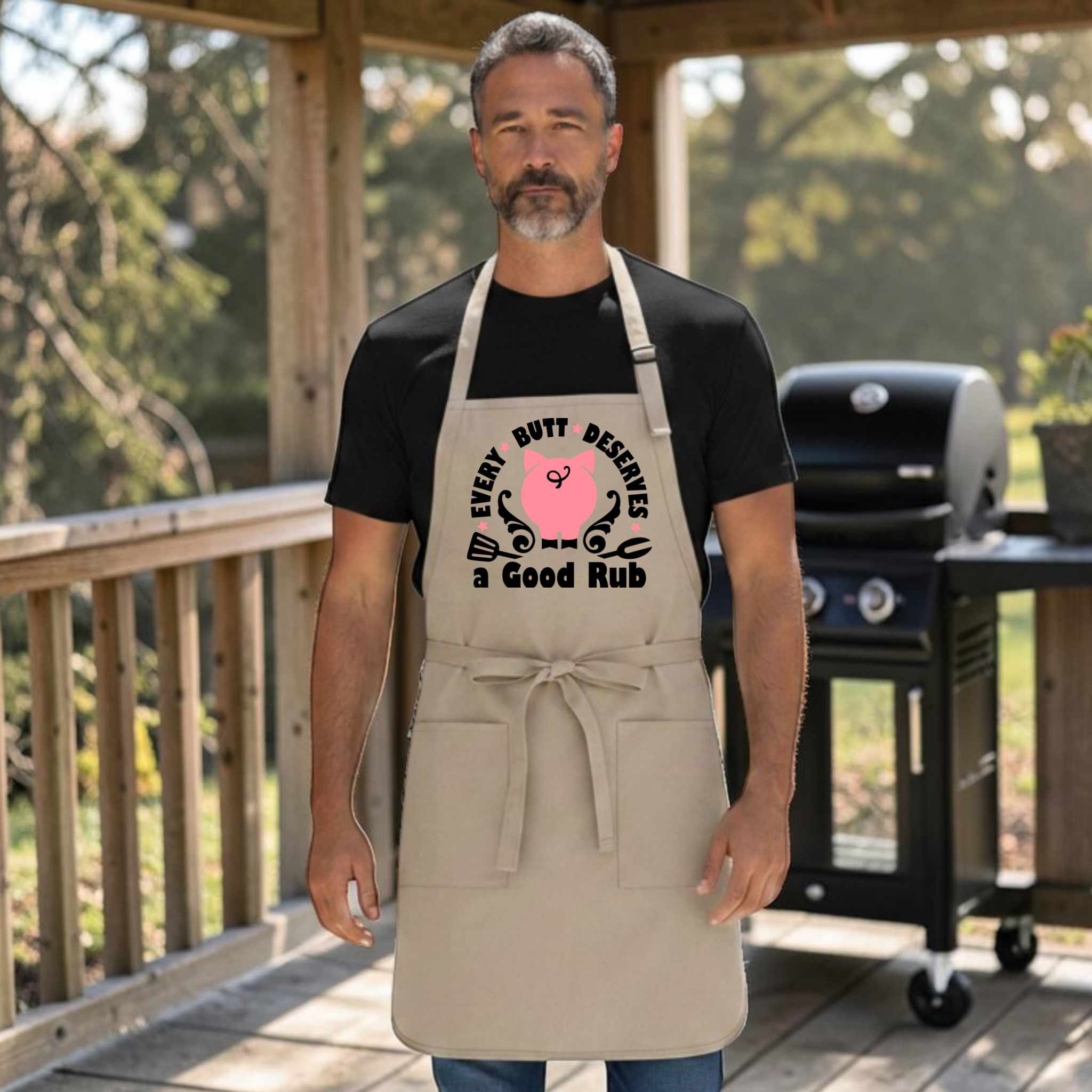 Khaki Port Authority A600 grilling apron with printed design of a pig's butt & grill utensils with the words every butt deserves a good rub