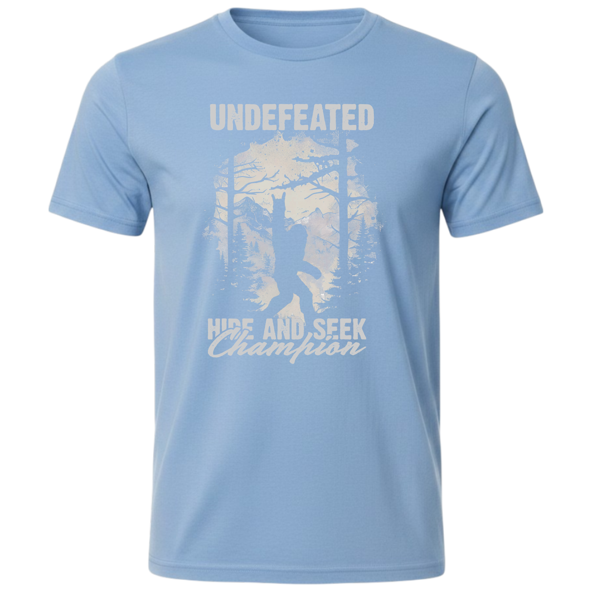 A light blue short-sleeve crewneck t-shirt featuring a light grey graphic of a Bigfoot silhouette in a forest, with the text 'UNDEFEATED' above and 'HIDE AND SEEK Champion' below.