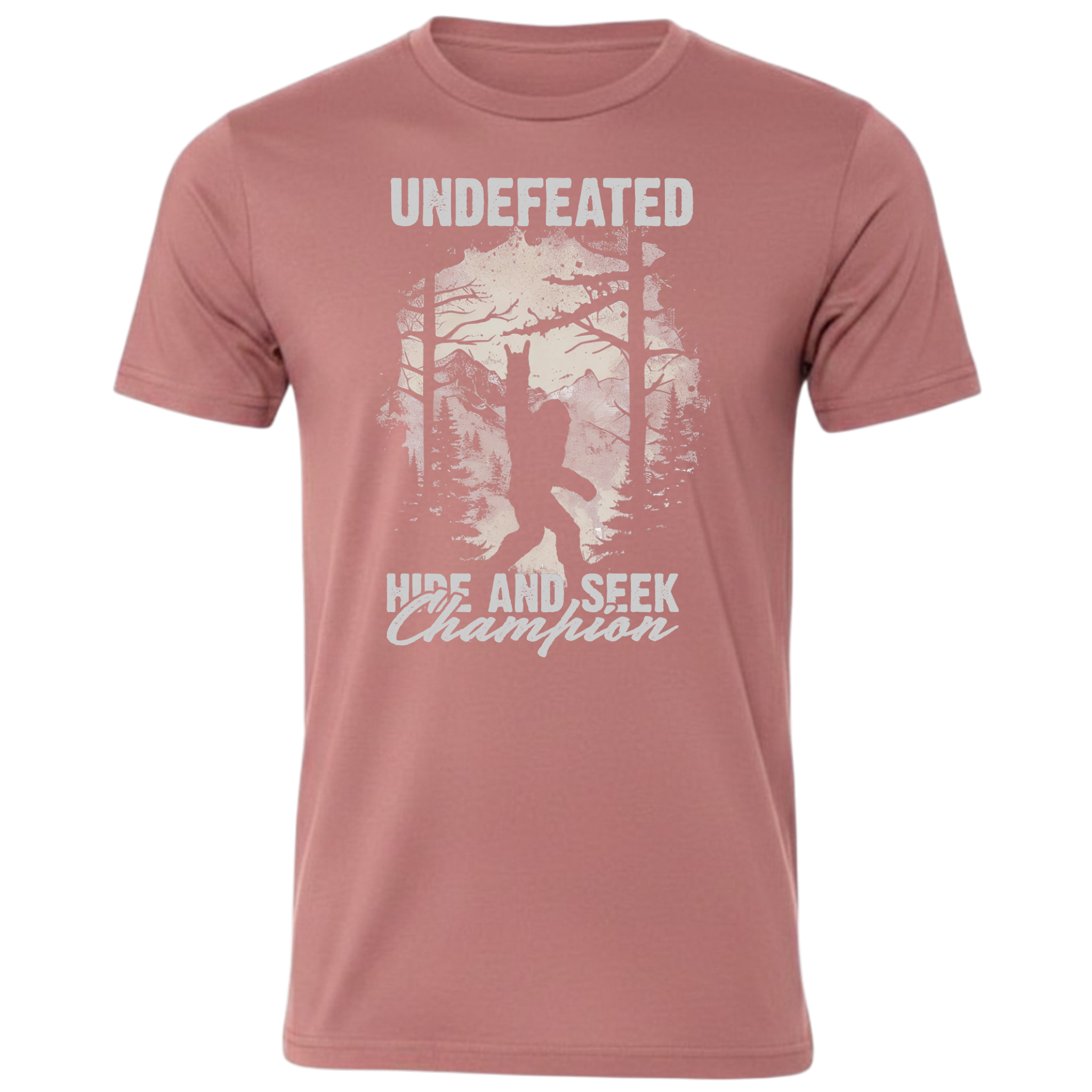 A mauve short-sleeve crewneck t-shirt featuring a light grey graphic print of a Bigfoot silhouette in a forest with the text 'UNDEFEATED' and 'HIDE AND SEEK Champion'.